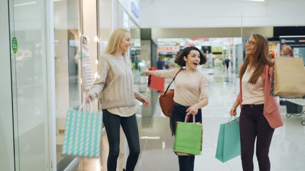 Three women with shopping bags in a mall.